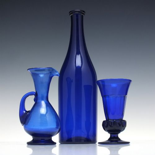 fig 1. A dark cobalt blue Victorian hand-blown glass serving bottle featuring a tapered neck, double collar, and smooth cylindrical body.