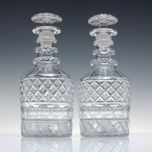fig 1. A pair of clear cut lead crystal Georgian decanters featuring diamond cut bands, neck rings, and mushroom stoppers.
