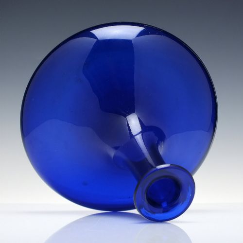 fig 2. A Georgian cobalt blue glass mell decanter with a wide rounded base, narrow neck, and a cork stopper with a metal ring labeled RUM.