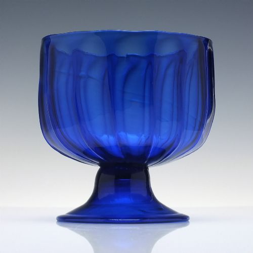 fig 1. A deep cobalt blue glass sugar bowl featuring a vertically ribbed body set upon a conical pedestal foot.