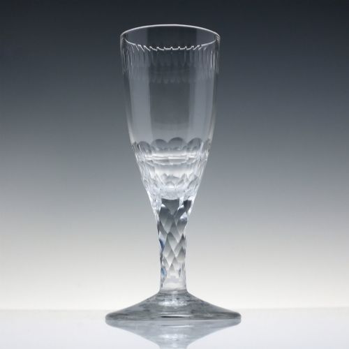 fig 1. An 18th-century clear lead crystal ale glass featuring a faceted stem, a wide conical foot, and geometric cut decoration on the bowl.