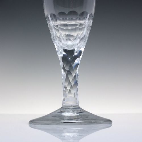 fig 2. An 18th-century clear lead crystal ale glass featuring a faceted stem, a wide conical foot, and geometric cut decoration on the bowl.