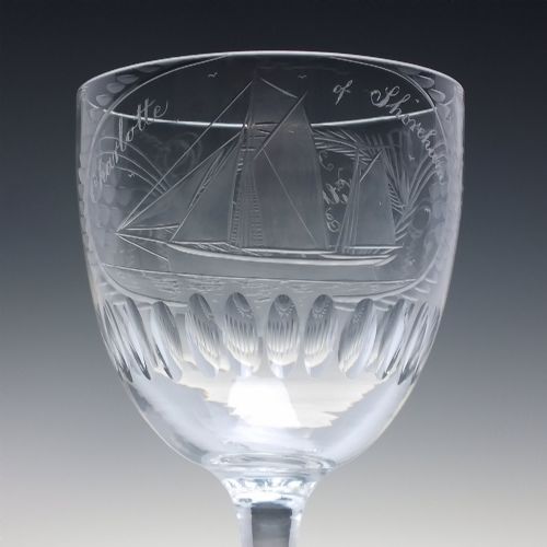 fig 3. A pair of clear glass Victorian wine goblets featuring wheel-engraved sailing ships, inscriptions, and cut oval fluting around the lower bowls.