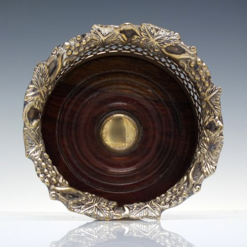 fig 1. A Victorian gilded and silver plate champagne bottle coaster featuring a pierced lattice gallery, flared rim, and dark wood base.
