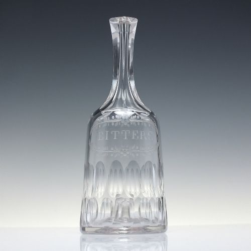fig 1. An 18th-century clear glass sugar loaf bitters bottle featuring a faceted slender neck, cut panel base, and wheel-engraved lettering spelling BITTERS surrounded by floral swags.