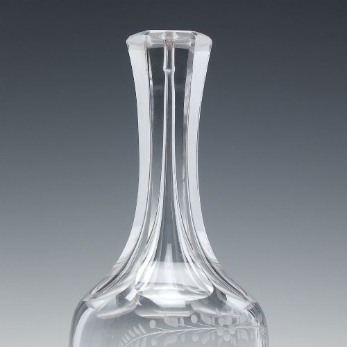 fig 2. An 18th-century clear glass sugar loaf bitters bottle featuring a faceted slender neck, cut panel base, and wheel-engraved lettering spelling BITTERS surrounded by floral swags.