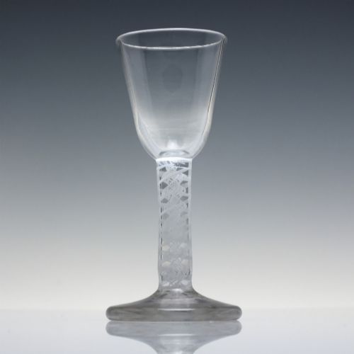 fig 1. An 18th-century clear glass wine glass featuring an internal white opaque twist stem and a thickened firing foot base.