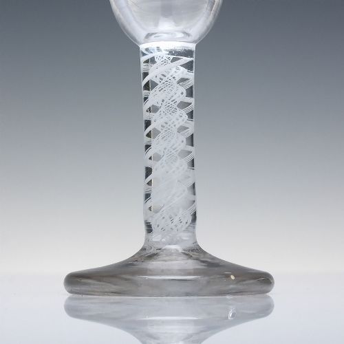 fig 2. An 18th-century clear glass wine glass featuring an internal white opaque twist stem and a thickened firing foot base.