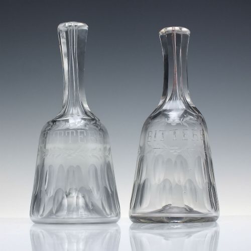 fig 1. A pair of 18th-century clear glass sugar loaf bitters bottles featuring facet-cut long necks, hand-engraved floral garlands, and the word BITTERS cut into the body.