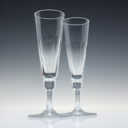 fig 2. A set of six Victorian clear cut glass champagne flutes arranged in a row, featuring tall conical bowls with basal panel cutting and faceted stems.