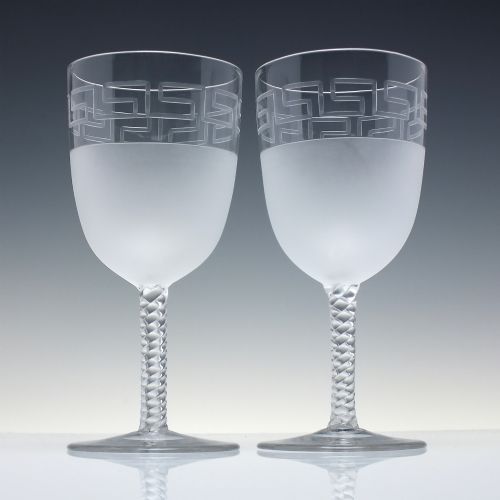 fig 1. A pair of clear and frosted Edwardian glass wine goblets featuring a Greek key engraved border and spiral twisted stems.