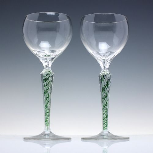 fig 1. A pair of clear glass wine goblets featuring round bowls and tall stems decorated with internal green and white opaque twists.