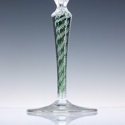 fig 3. A pair of clear glass wine goblets featuring round bowls and tall stems decorated with internal green and white opaque twists.