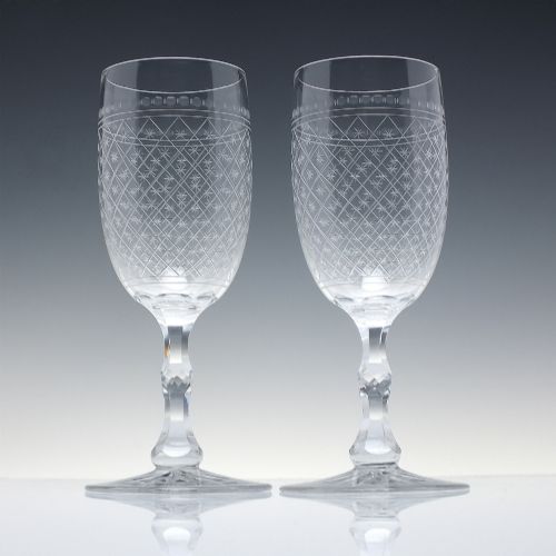 fig 1. A pair of clear glass Victorian wine goblets featuring star and diamond pattern engravings with faceted stems.