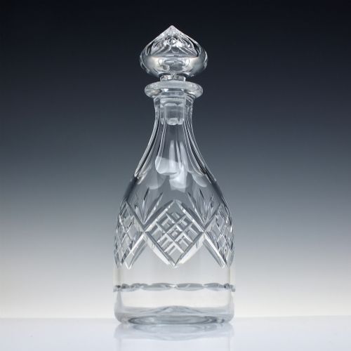 fig 1. A clear cut crystal glass decanter with a geometric diamond cut body, smooth neck, and faceted glass stopper.