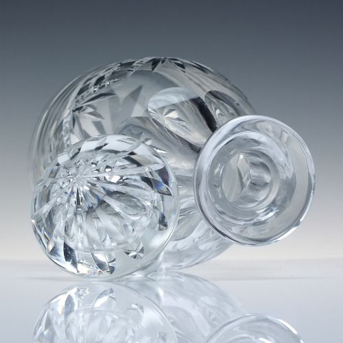 fig 3. A clear cut crystal glass decanter with a geometric diamond cut body, smooth neck, and faceted glass stopper.