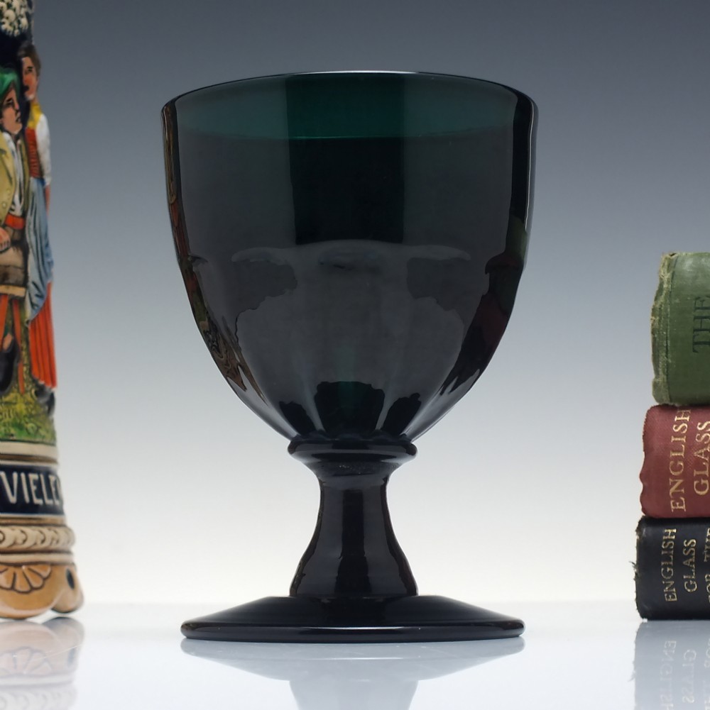 A dark green Georgian glass rummer featuring a fluted bowl, short knopped stem, and circular foot.
