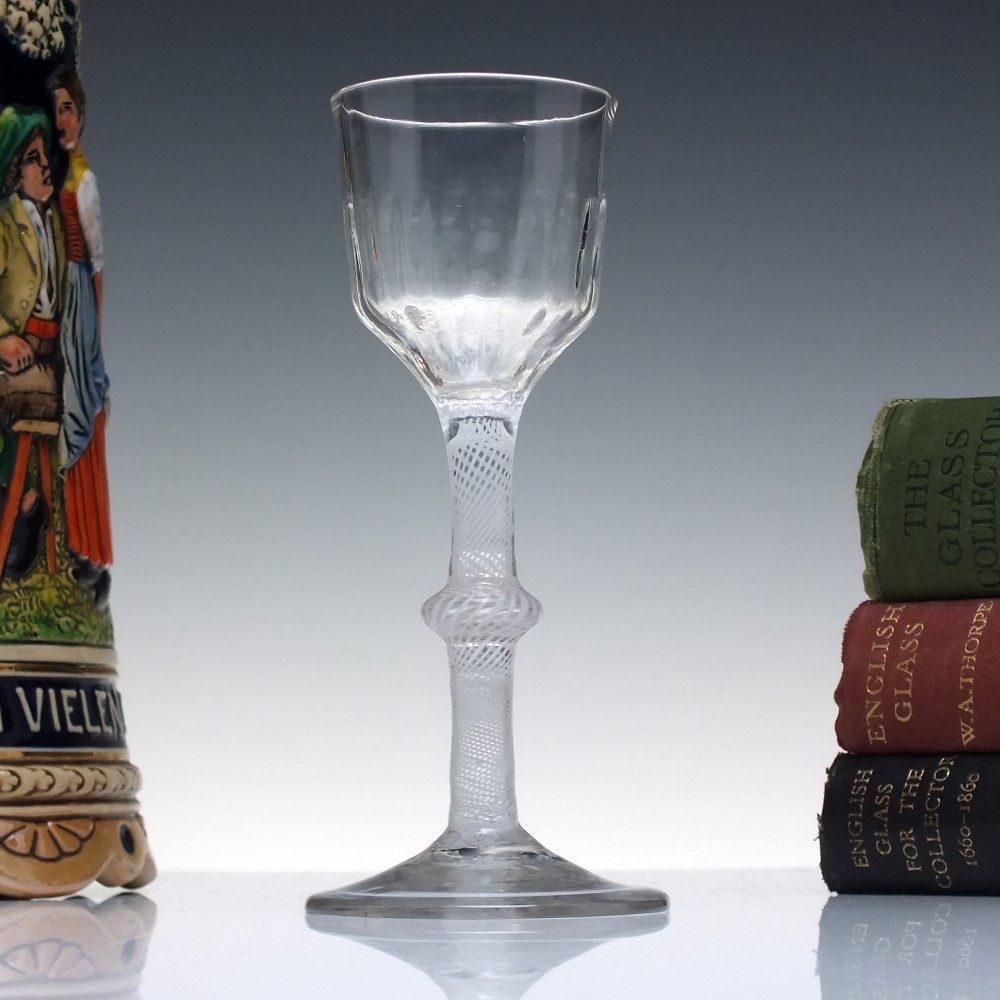 An 18th-century clear glass wine glass featuring a multi-spiral opaque white twist stem with a central knop and a round foot.