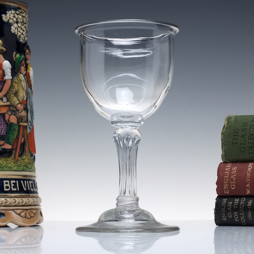 An 18th-century clear glass goblet featuring a bucket bowl supported by a ribbed pedestal stem and a flared round foot.