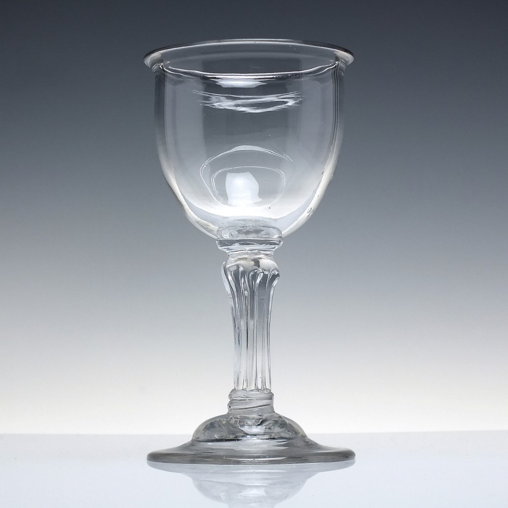 An 18th-century clear glass goblet featuring a bucket bowl supported by a ribbed pedestal stem and a flared round foot. View II