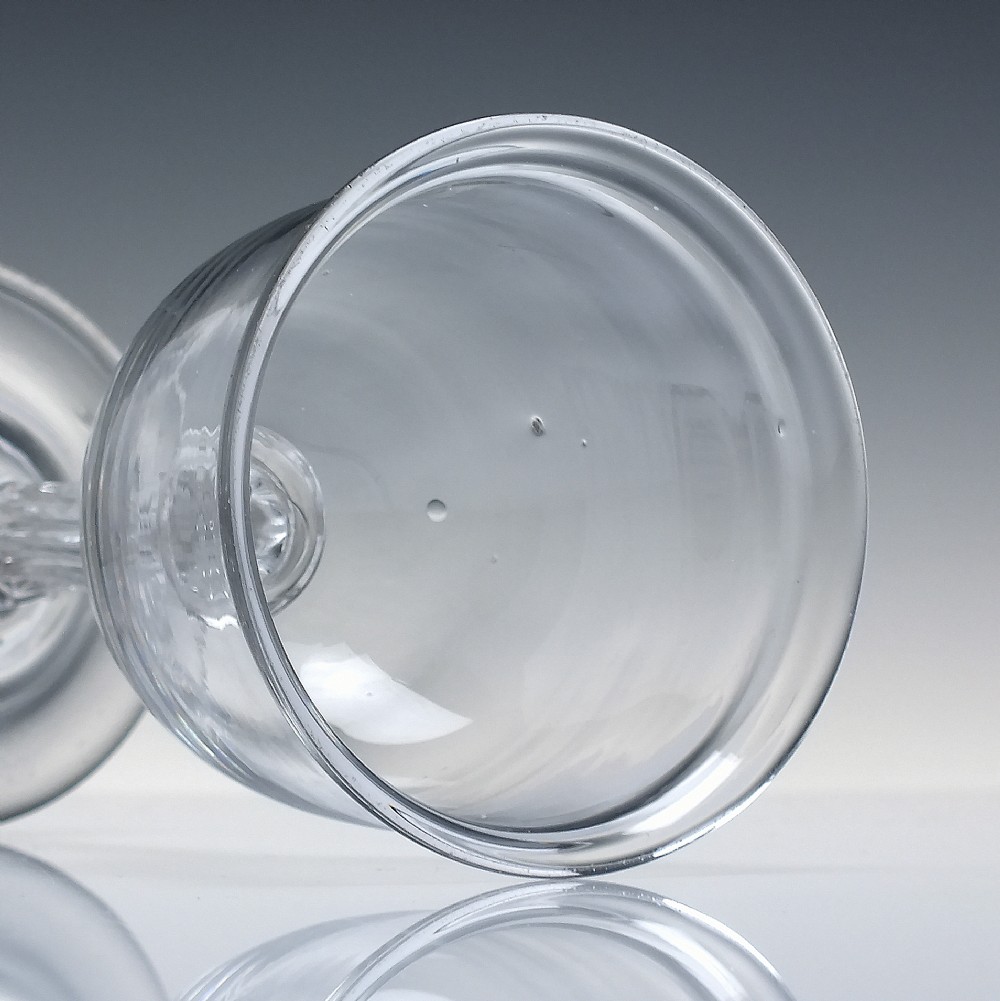 An 18th-century clear glass goblet featuring a bucket bowl supported by a ribbed pedestal stem and a flared round foot. View V
