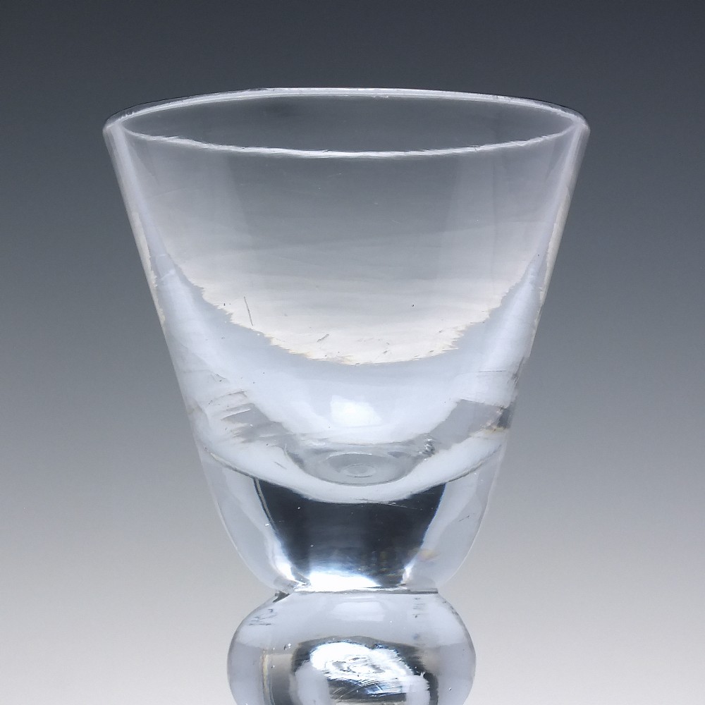 An early 18th-century clear lead glass dram vessel featuring a trumpet-shaped bowl and a heavy baluster knopped stem on a circular foot. View IV