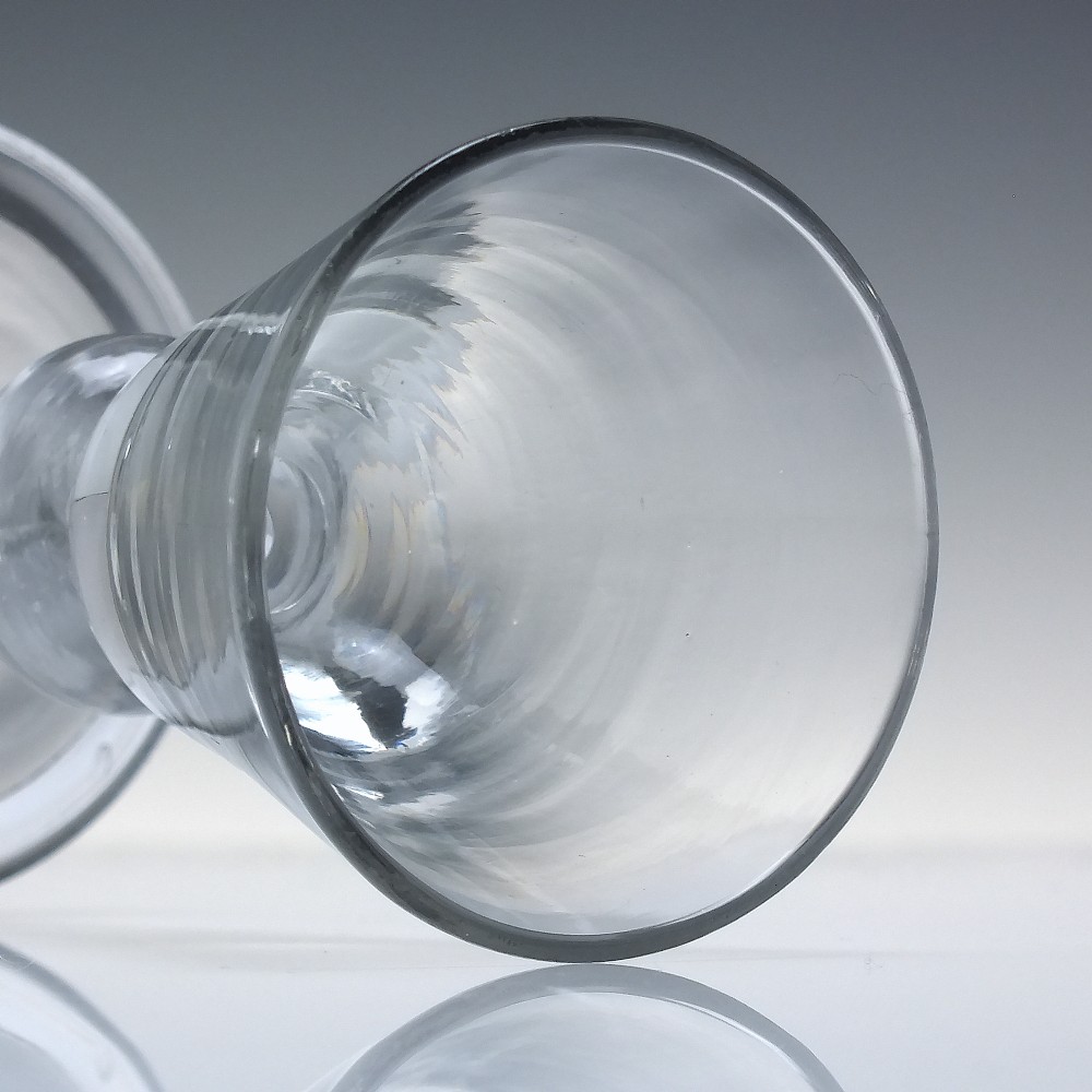 An early 18th-century clear lead glass dram vessel featuring a trumpet-shaped bowl and a heavy baluster knopped stem on a circular foot. View V