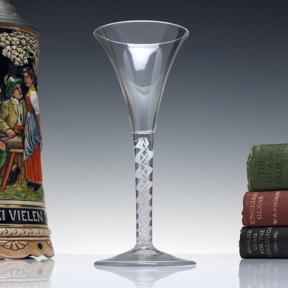A Georgian wine glass featuring a clear trumpet-shaped bowl resting on a straight stem with an internal white opaque double series twist spiral and a conical foot.
