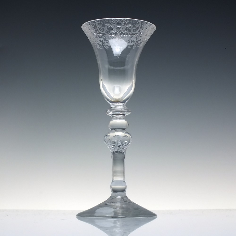 An 18th-century clear glass wine goblet featuring a wheel-engraved Rococo rim, a light baluster stem with knops, and a conical foot. View II