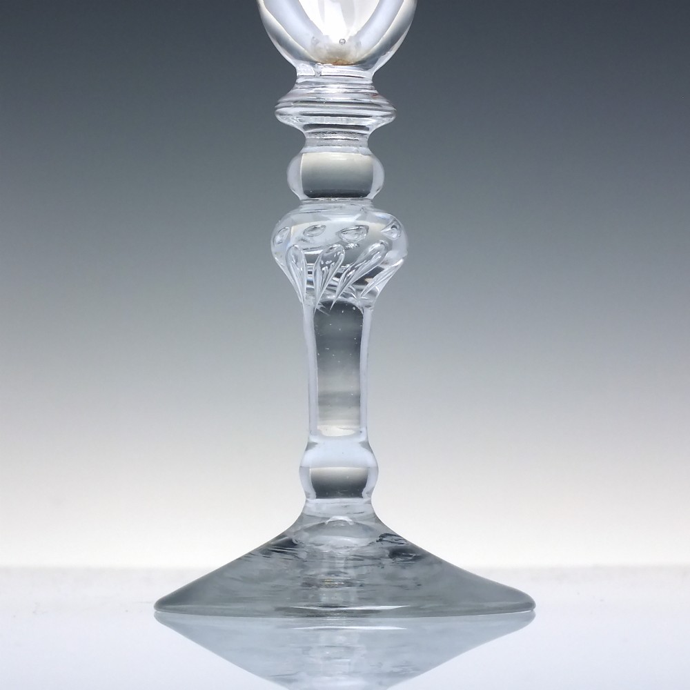 An 18th-century clear glass wine goblet featuring a wheel-engraved Rococo rim, a light baluster stem with knops, and a conical foot. View III