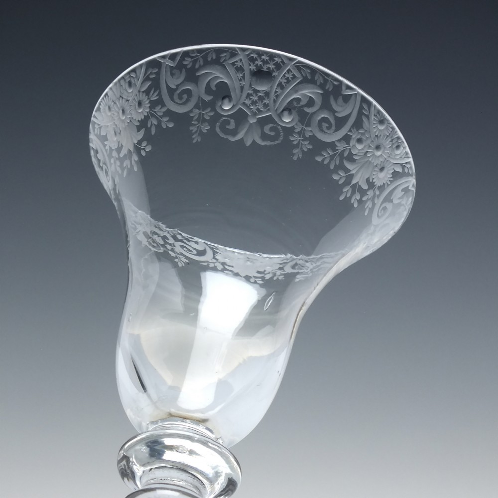 An 18th-century clear glass wine goblet featuring a wheel-engraved Rococo rim, a light baluster stem with knops, and a conical foot. View IV