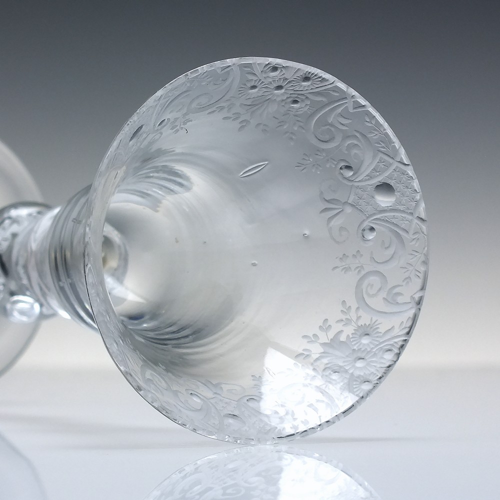 An 18th-century clear glass wine goblet featuring a wheel-engraved Rococo rim, a light baluster stem with knops, and a conical foot. View VI
