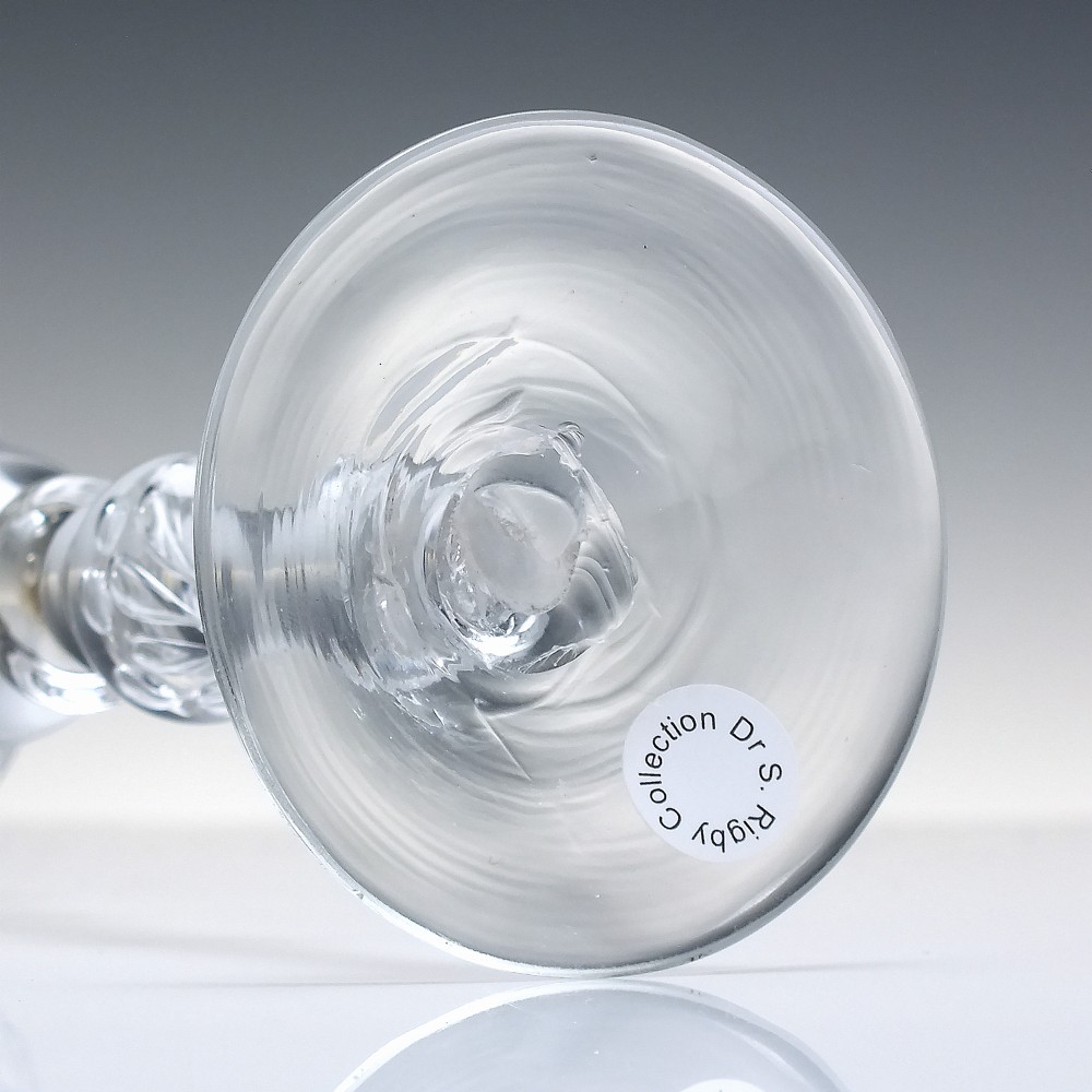 An 18th-century clear glass wine goblet featuring a wheel-engraved Rococo rim, a light baluster stem with knops, and a conical foot. View VII