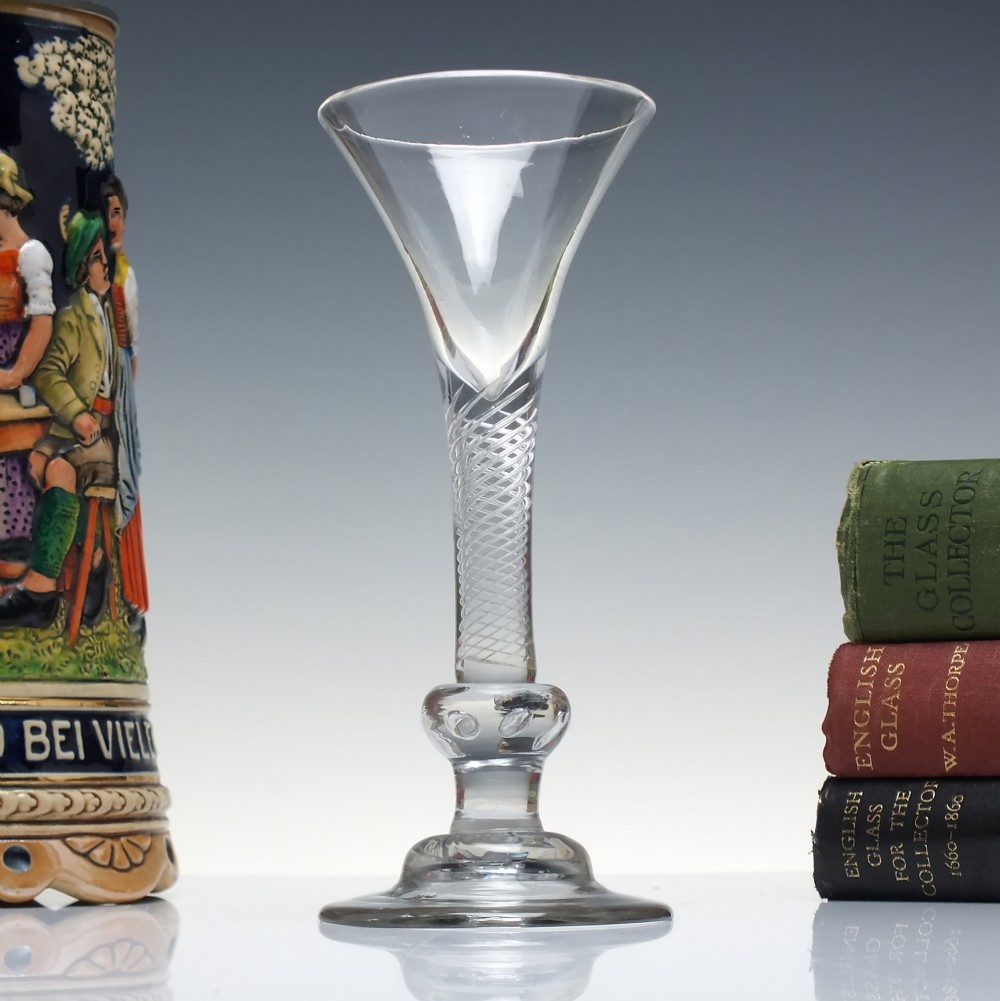 An 18th-century Georgian clear lead glass wine glass featuring a flared bell bowl, an air twist stem with a central knop, and a wide domed foot.