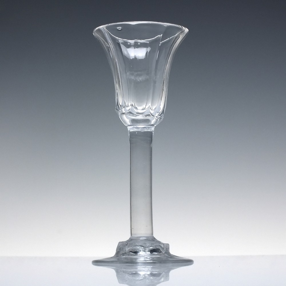 An 18th-century clear lead glass wine goblet featuring an inverted petal moulded bowl, a tall plain stem, and a circular foot. View II