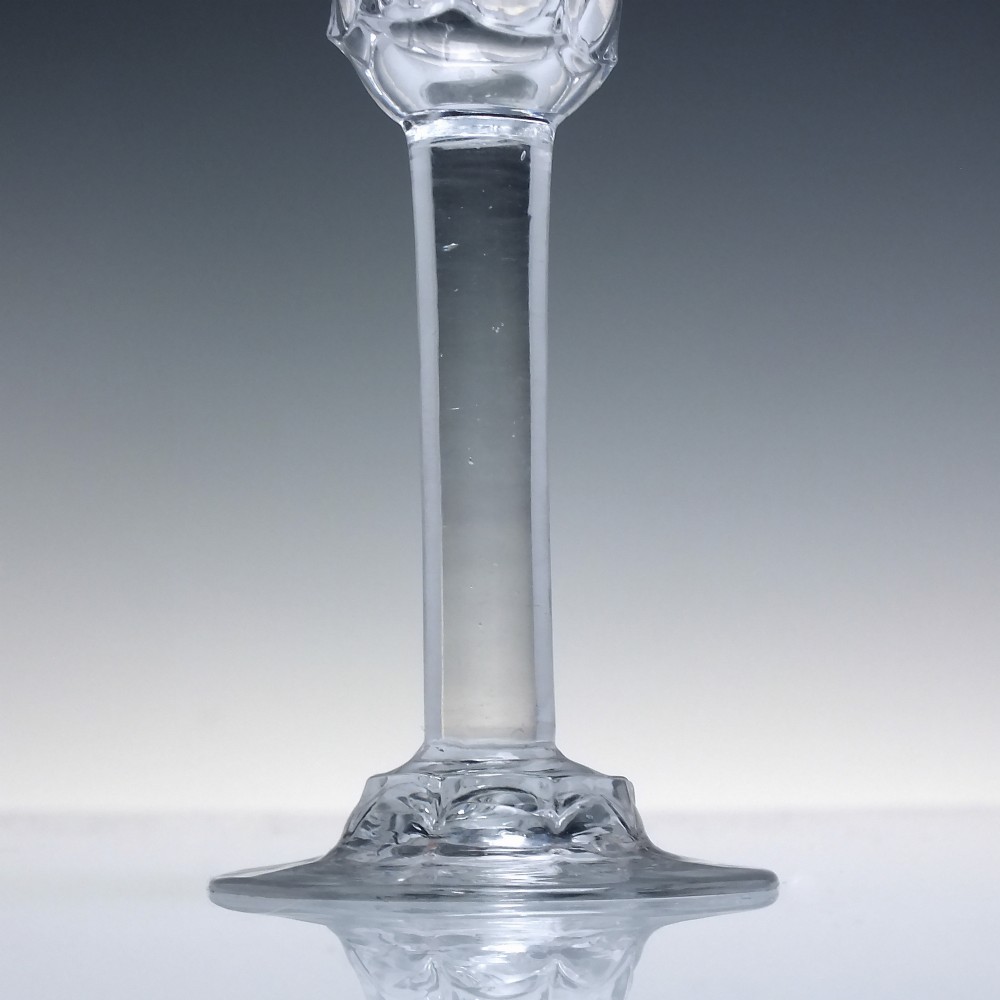 An 18th-century clear lead glass wine goblet featuring an inverted petal moulded bowl, a tall plain stem, and a circular foot. View IV