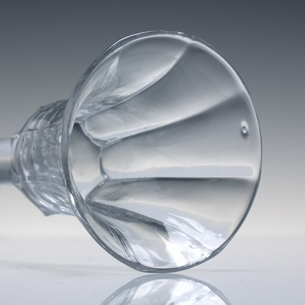 An 18th-century clear lead glass wine goblet featuring an inverted petal moulded bowl, a tall plain stem, and a circular foot. View VI