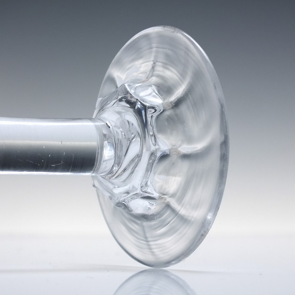 An 18th-century clear lead glass wine goblet featuring an inverted petal moulded bowl, a tall plain stem, and a circular foot. View VII
