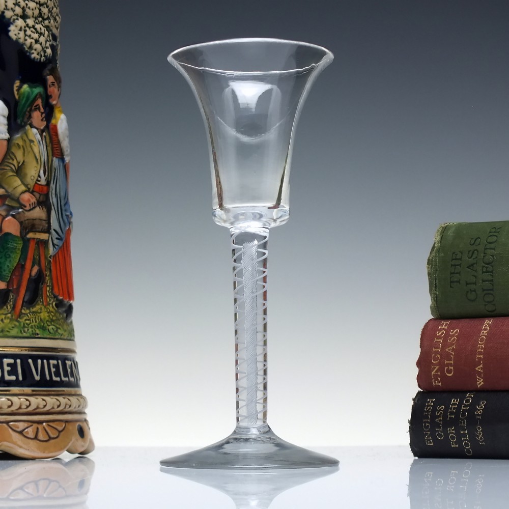 An eighteenth-century clear lead glass wine glass featuring a flared bucket bowl and a mixed twist stem on a conical foot.