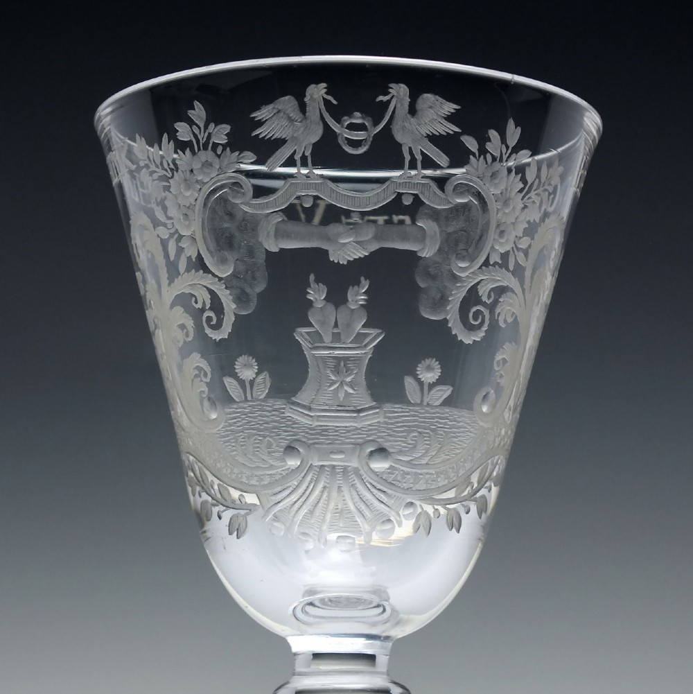 An 18th-century clear lead glass wine goblet featuring detailed wheel-engraved marriage motifs on the bowl and a knopped light baluster stem. View III