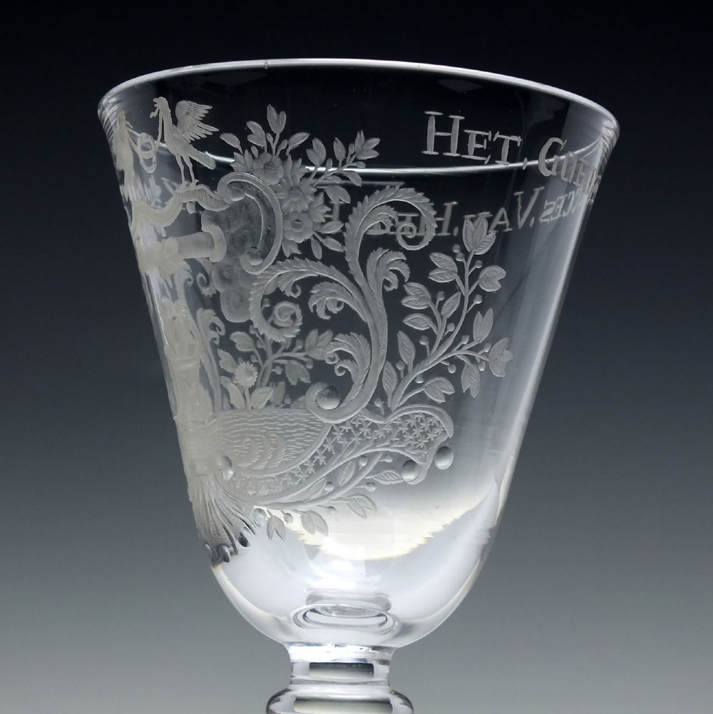 An 18th-century clear lead glass wine goblet featuring detailed wheel-engraved marriage motifs on the bowl and a knopped light baluster stem. View VII