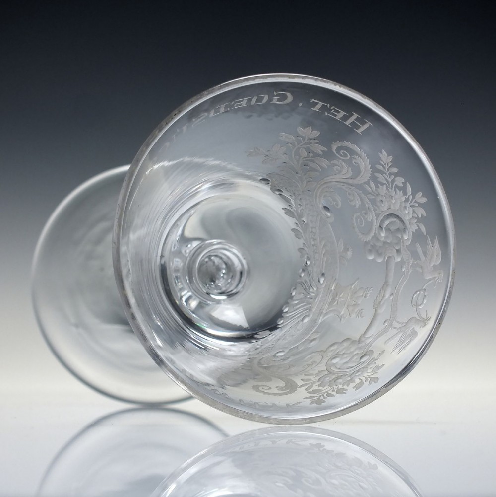 An 18th-century clear lead glass wine goblet featuring detailed wheel-engraved marriage motifs on the bowl and a knopped light baluster stem. View X
