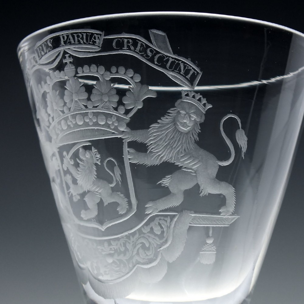 An 18th-century clear glass wine goblet with a wheel-engraved heraldic coat of arms on the bowl, a moulded pedestal stem, and a flat circular foot. View VI