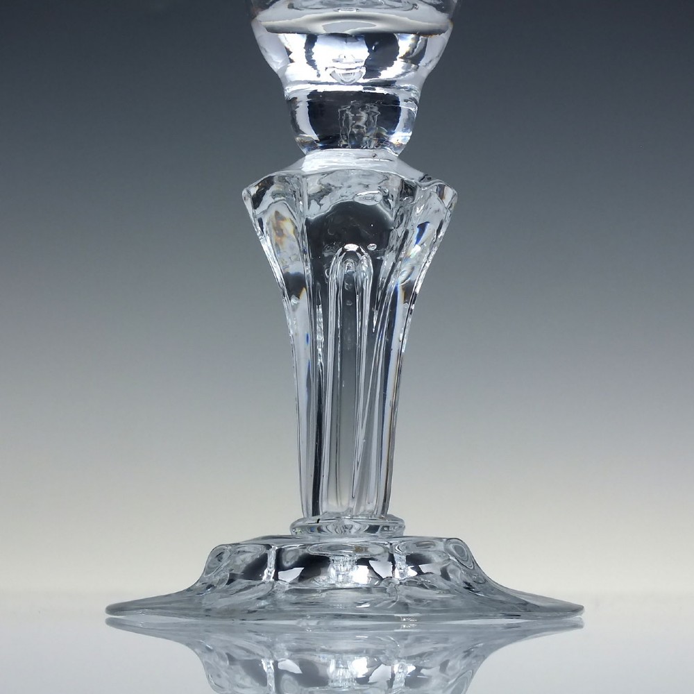 An 18th-century clear glass wine goblet with a wheel-engraved heraldic coat of arms on the bowl, a moulded pedestal stem, and a flat circular foot. View VII