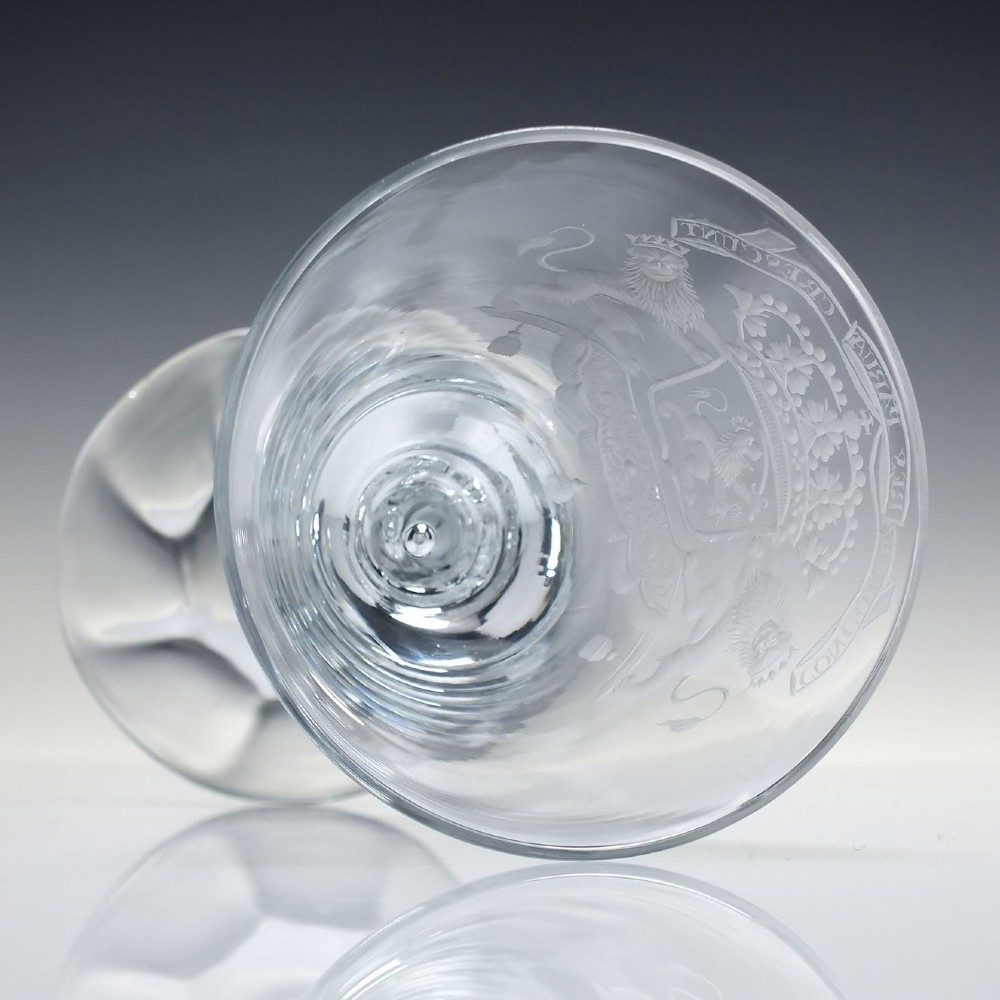 An 18th-century clear glass wine goblet with a wheel-engraved heraldic coat of arms on the bowl, a moulded pedestal stem, and a flat circular foot. View VIII