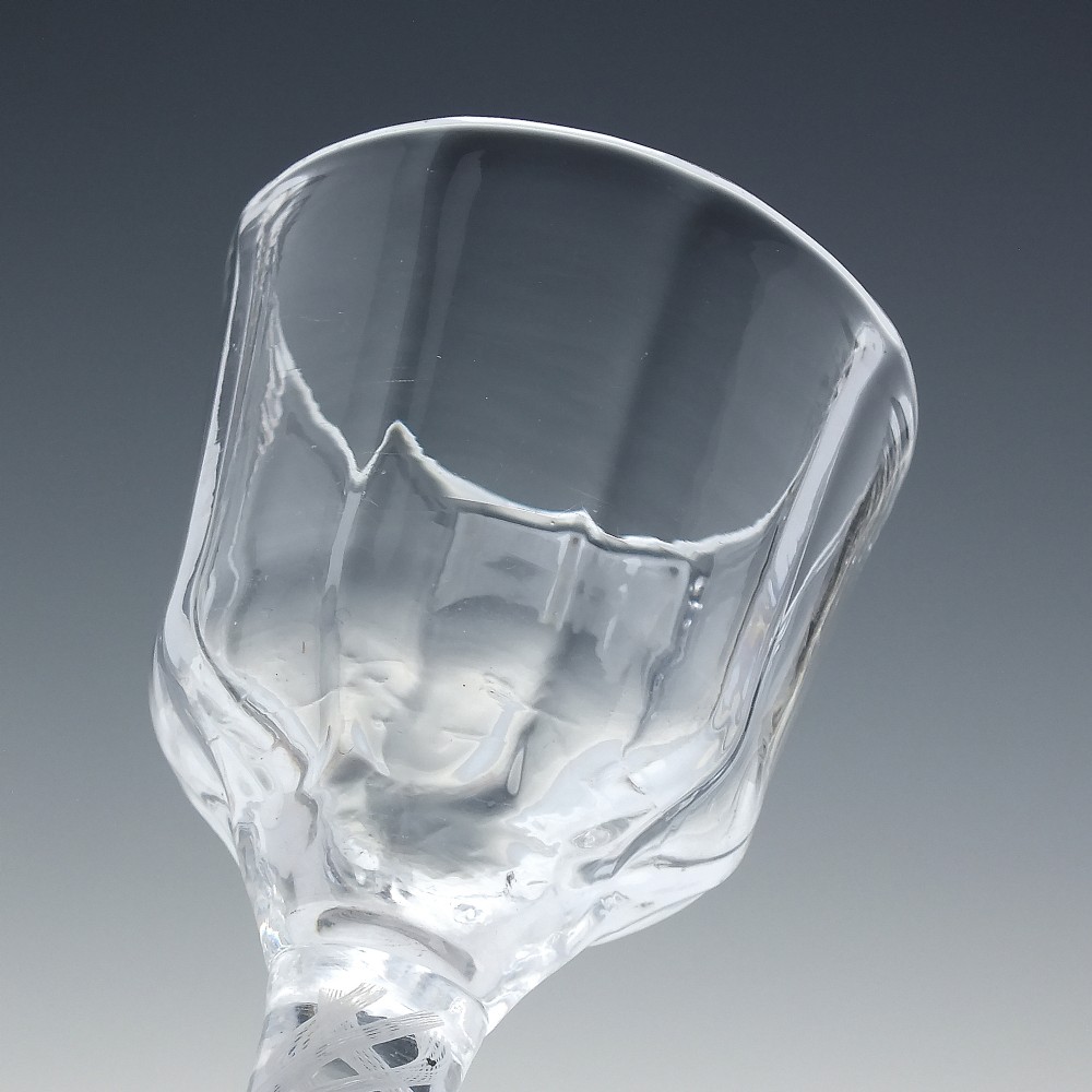 An 18th-century clear glass wine vessel featuring a ribbed ogee bowl supported by a stem with an internal white opaque twist motif resting on a conical foot. View IV