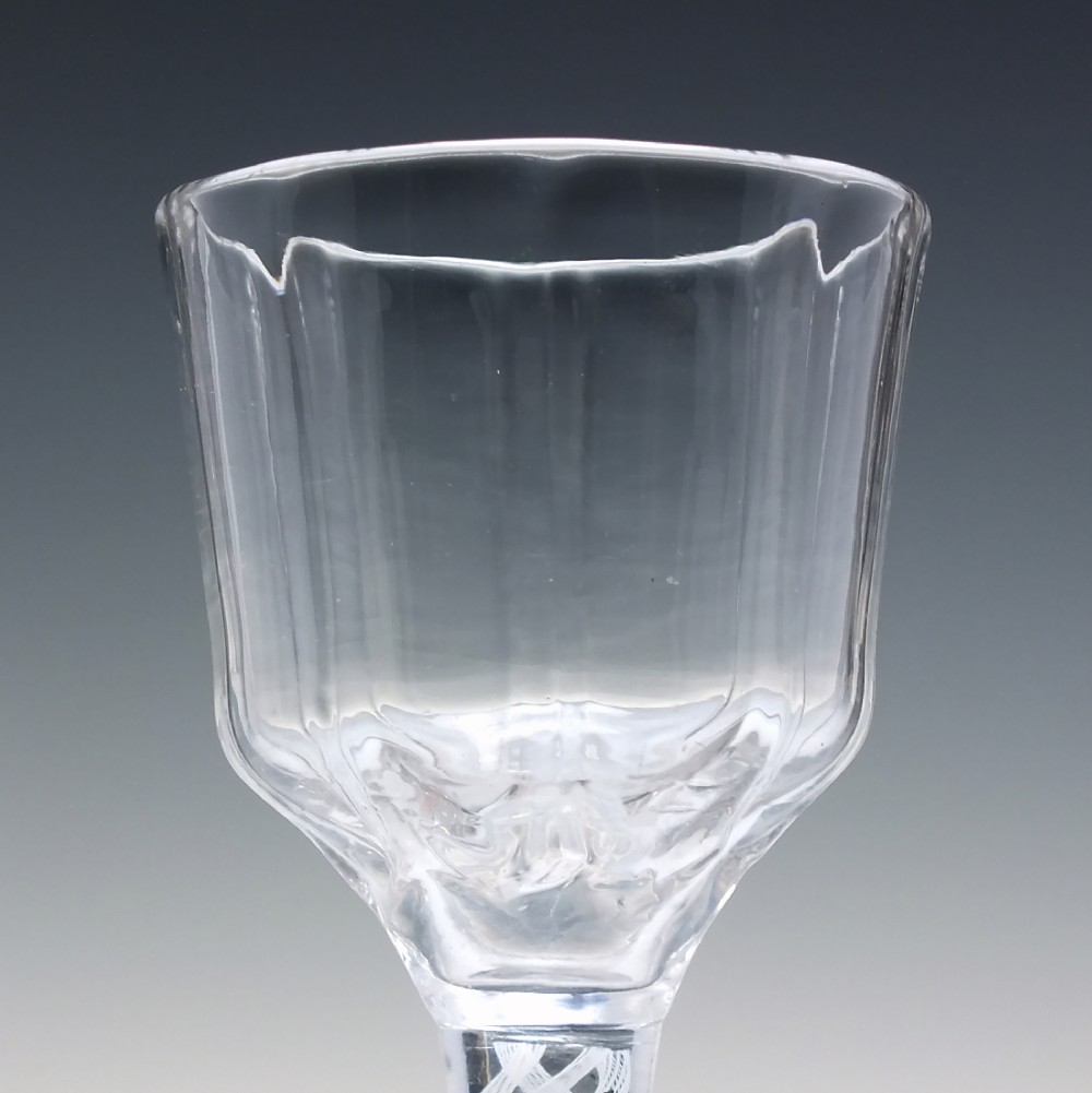 An 18th-century clear glass wine vessel featuring a ribbed ogee bowl supported by a stem with an internal white opaque twist motif resting on a conical foot. View V