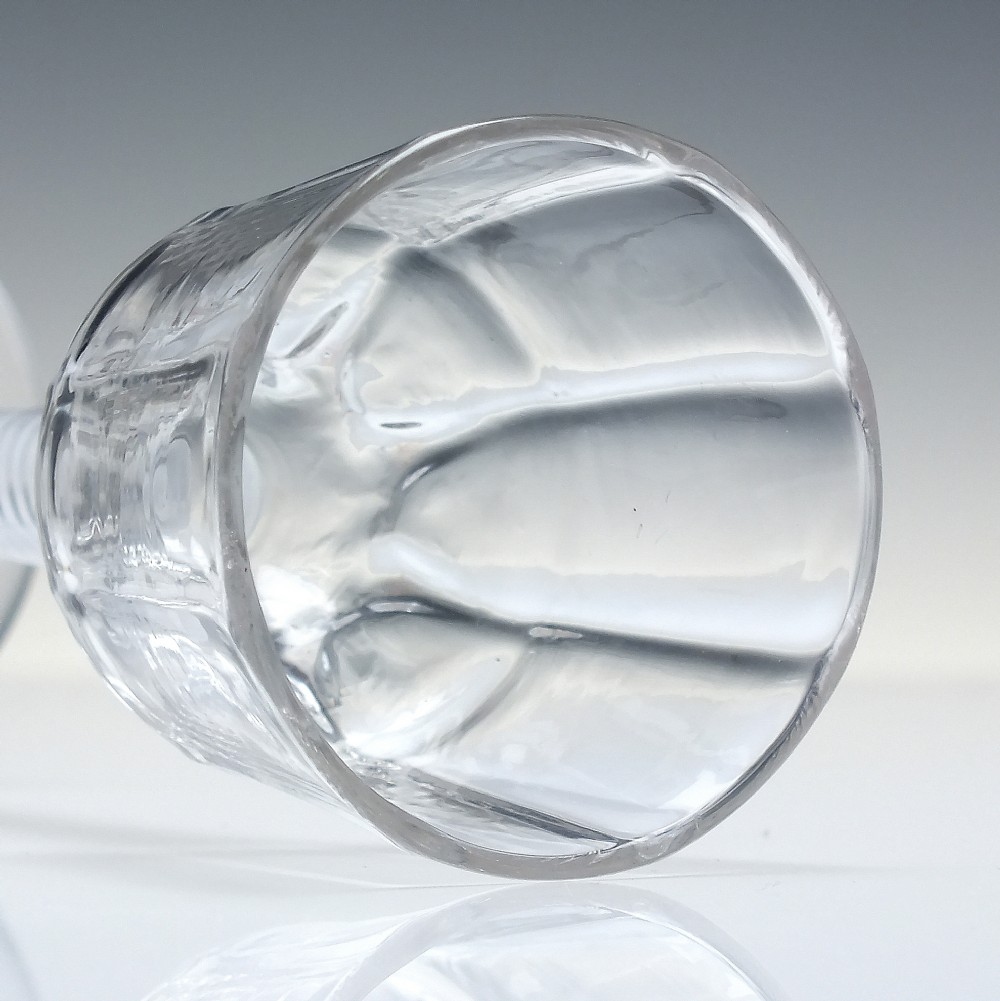 An 18th-century clear glass wine vessel featuring a ribbed ogee bowl supported by a stem with an internal white opaque twist motif resting on a conical foot. View VI