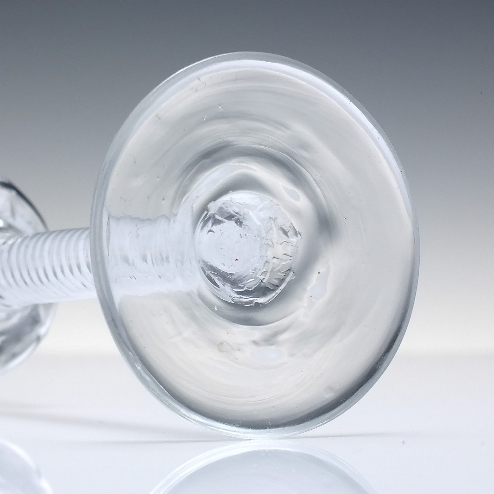 An 18th-century clear glass wine vessel featuring a ribbed ogee bowl supported by a stem with an internal white opaque twist motif resting on a conical foot. View VII