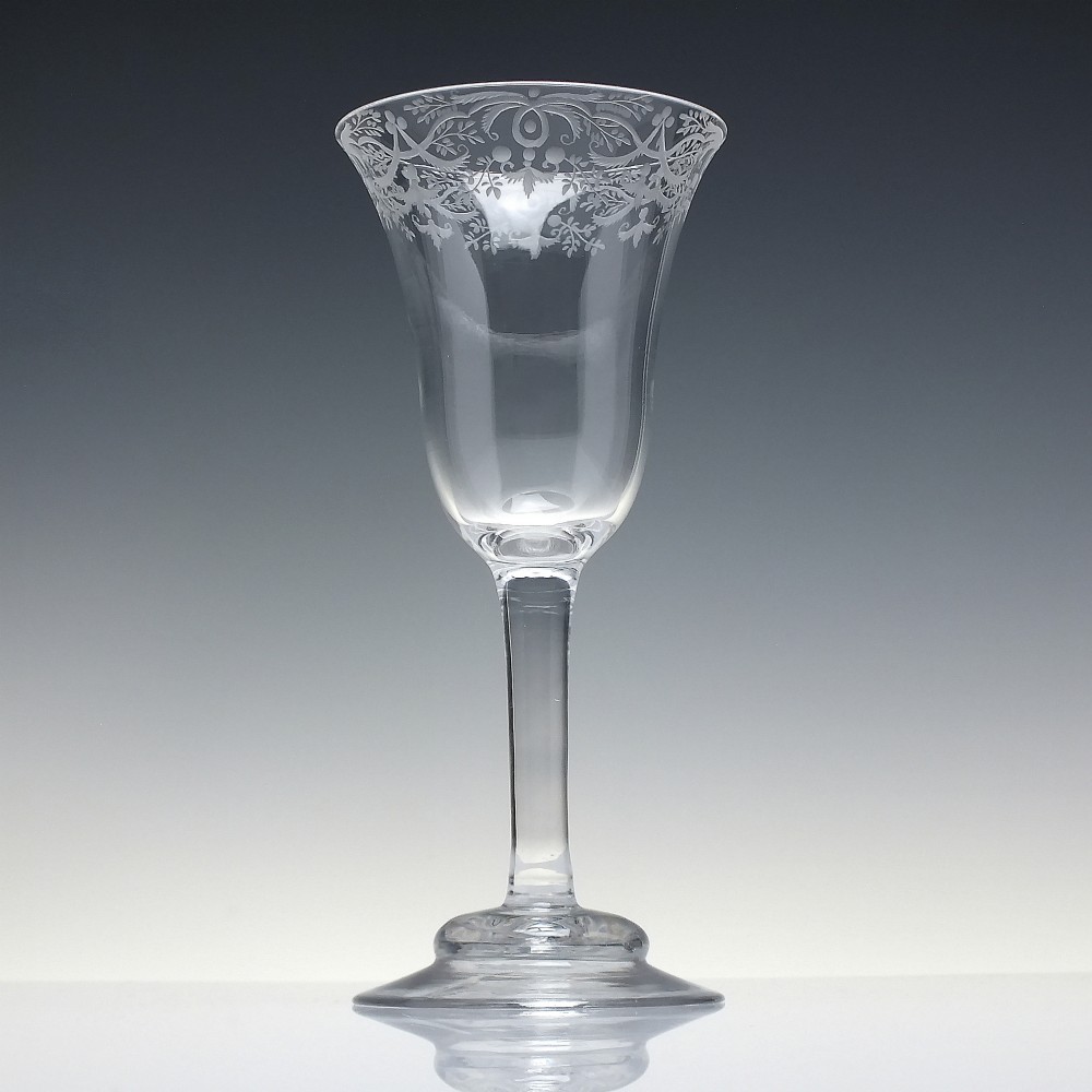 A clear 18th-century lead glass goblet featuring an engraved scroll border along the rim, a plain stem, and a circular foot. View II
